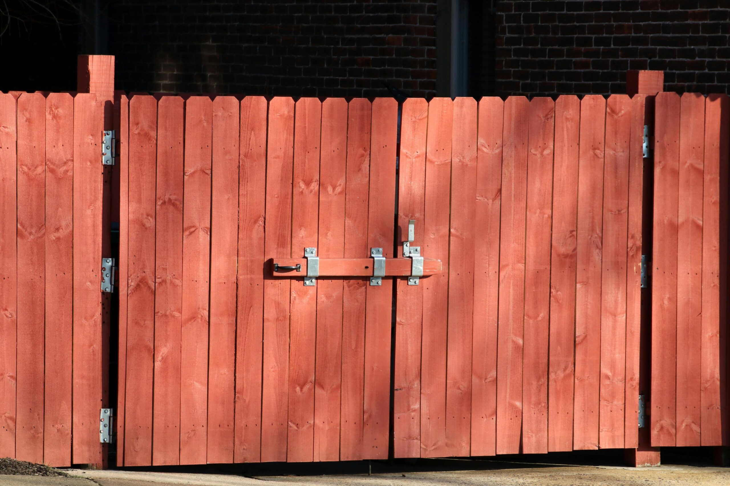 Home Rustic red wooden fence with a metal latch, ensuring safety and security outdoors.