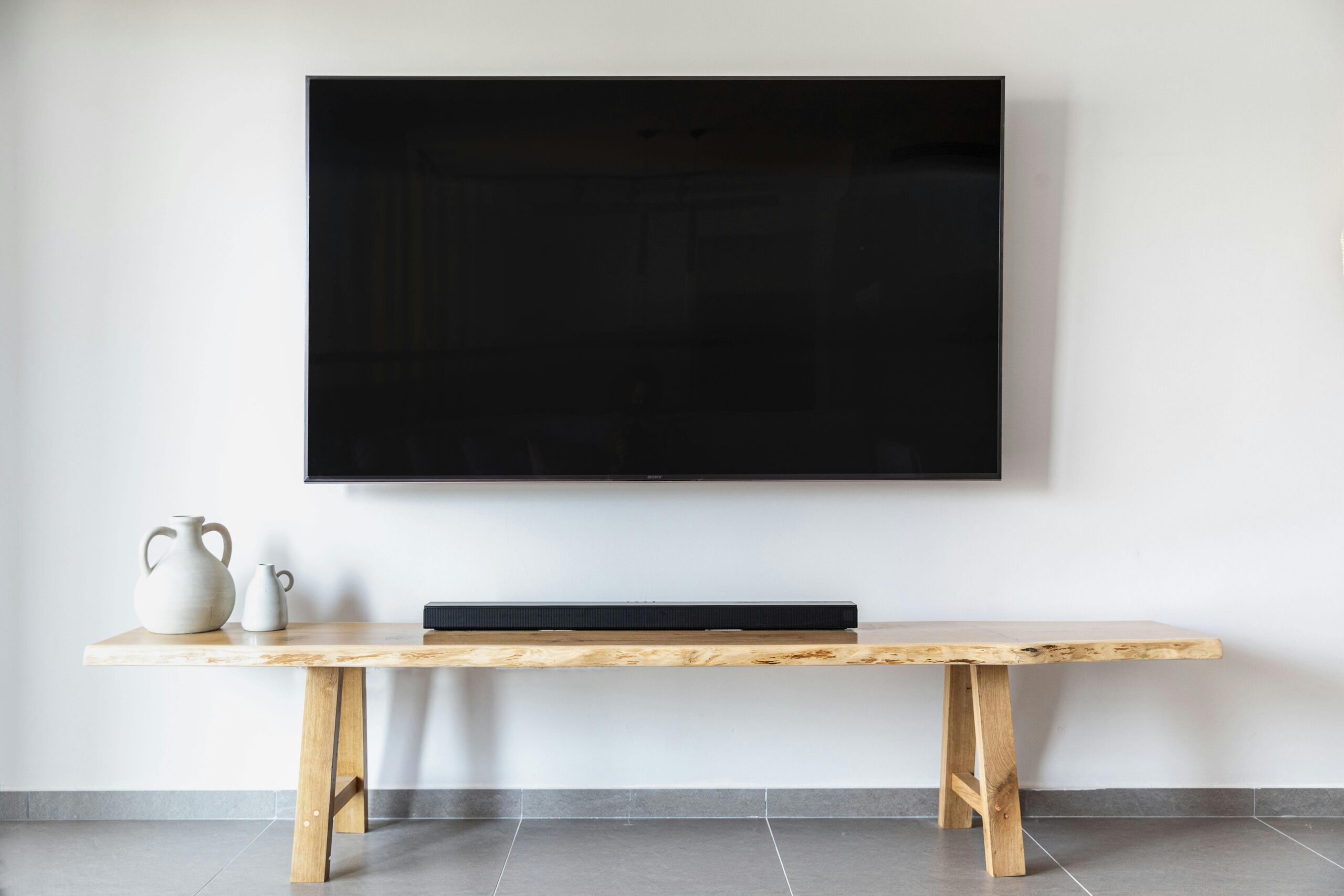 Home Stylish minimalist living room featuring a wall-mounted flat screen TV and wooden console.