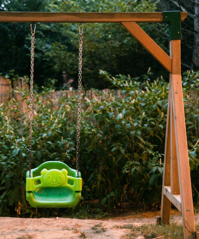 Home A vibrant green swing hanging in a peaceful garden, ready for playful moments.